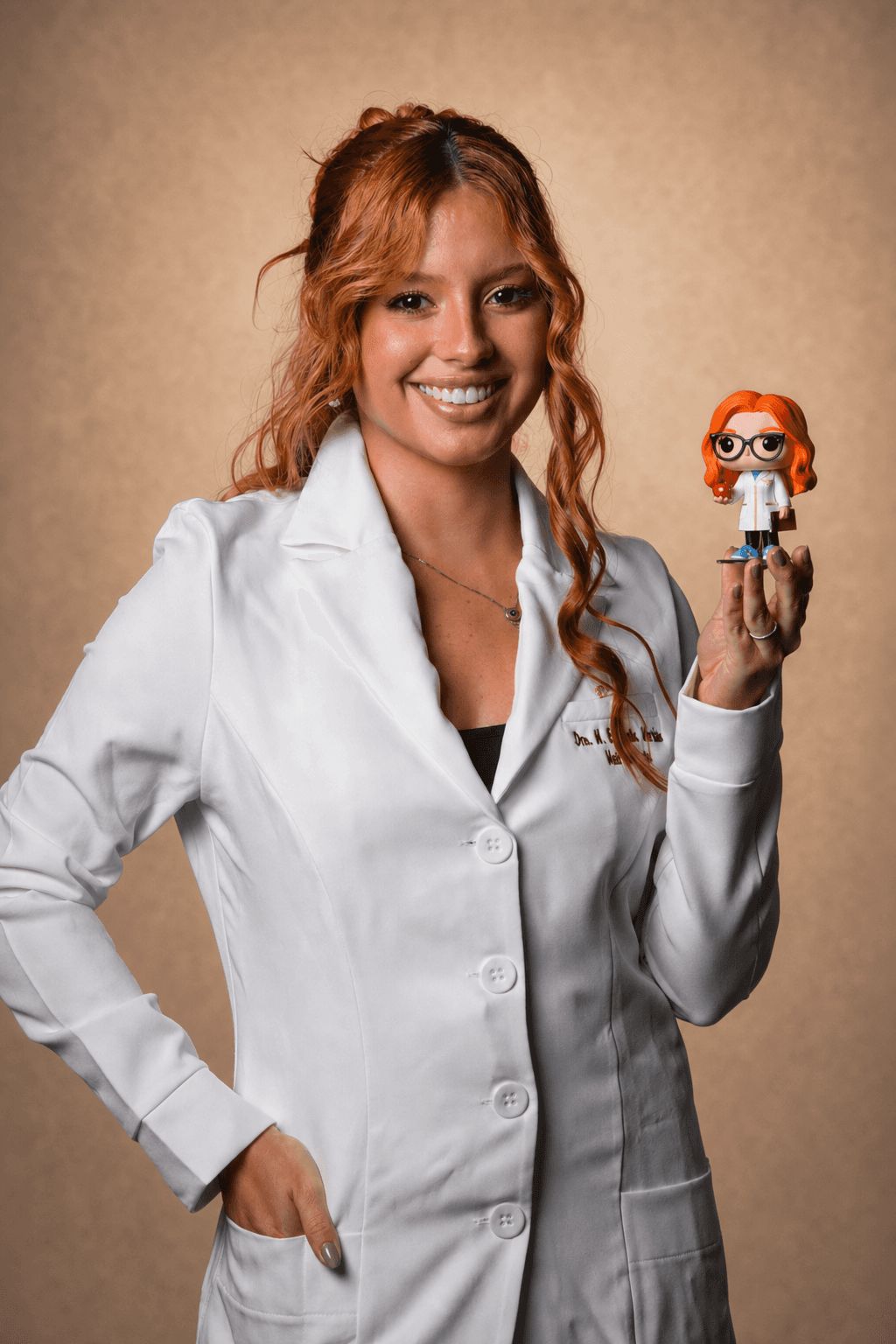 Maria Eduarda de jaleco segurando uma miniatura de si mesma